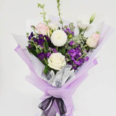 Bouquet of white and purple flowers wrapped in lavender paper