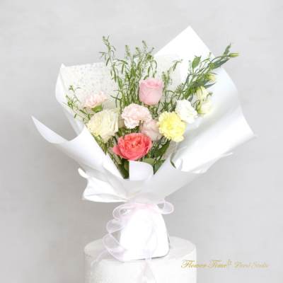 Bouquet of pastel roses and carnations wrapped in white paper