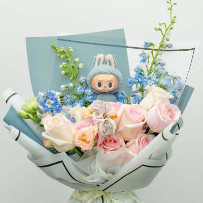 Bouquet of pink and white roses with blue flowers and a plush character centerpiece
