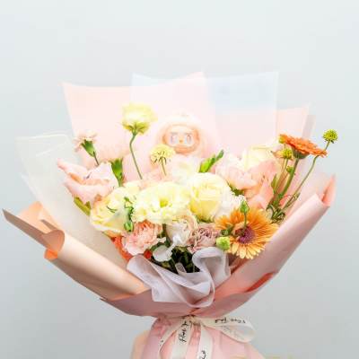 Pastel bouquet of roses, carnations, and gerbera daisies wrapped in pink paper