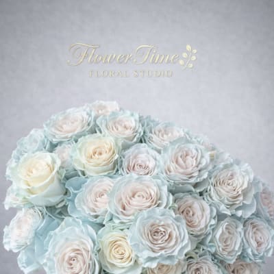 Large bouquet of pale blue and blush roses in a white basket