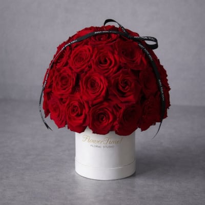 Red rose arrangement in a white hat box with a black ribbon