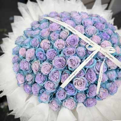 Large bouquet of lavender roses wrapped in white paper with a ribbon