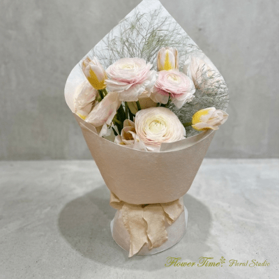 Bouquet of pale pink and white flowers wrapped in beige paper