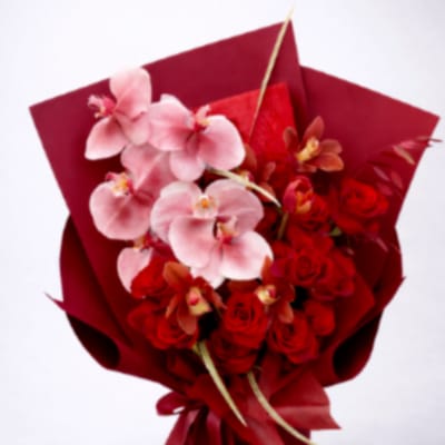 Bouquet of pink orchids and red roses wrapped in red paper
