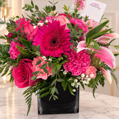 Pink and white mixed bouquet in a black vase with a birthday card