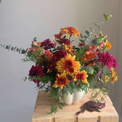 Colorful mixed bouquet in a white vase on a wooden table