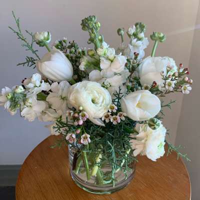 White floral bouquet in a clear glass vase on a wooden table