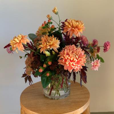 Peach and pink chrysanthemum arrangement in a clear glass vase
