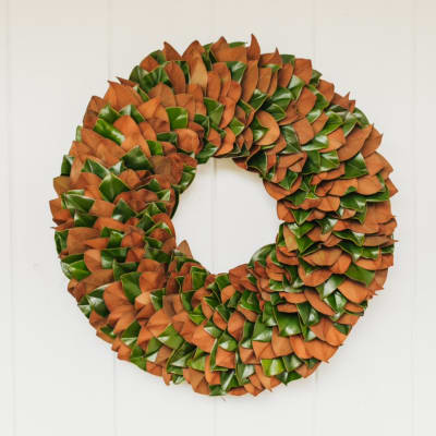 Round wreath of orange and green leaves on a white door