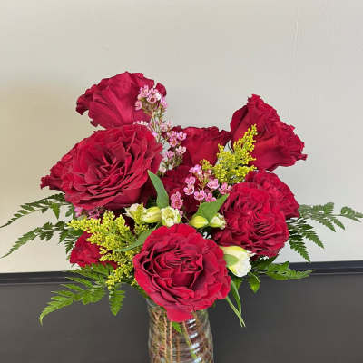 Red rose bouquet in a clear glass vase with small pink accent flowers