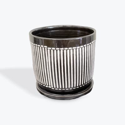Black ceramic planter with white vertical stripe pattern and saucer