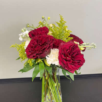 Red roses and white flowers in a clear glass vase