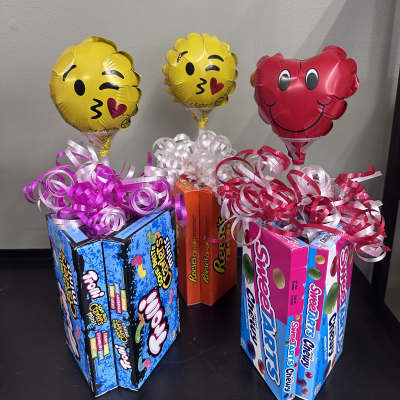 Candy gift boxes topped with emoji balloons and curly ribbon