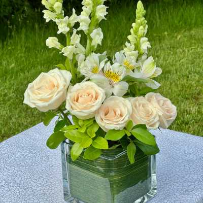 Cream roses and white snapdragons in a glass vase