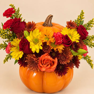 Fall floral arrangement in a pumpkin-shaped container with roses and mums