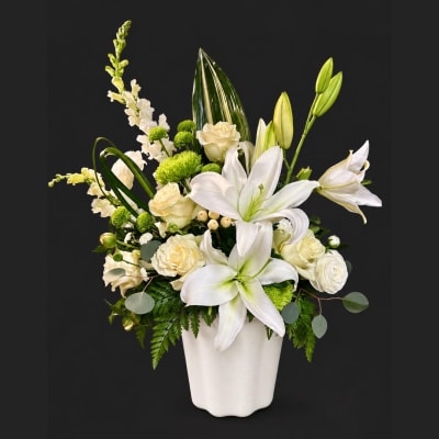 White lilies and cream roses arranged in a white vase