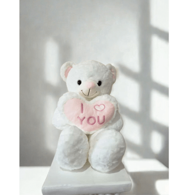 White teddy bear holding a pink heart that says I love you