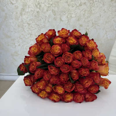 Large bouquet of red and orange roses on a white surface