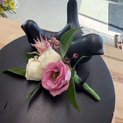 Small boutonniere with pink and white flowers on a black display stand