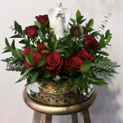 Basket arrangement of red roses with a white angel figurine