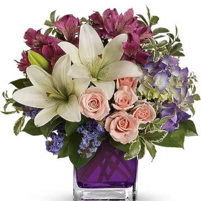 Bouquet of white lilies, pink roses, and purple flowers in a purple vase