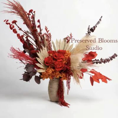 Tall asymmetrical arrangement of red roses and dried botanicals in a neutral ceramic vase