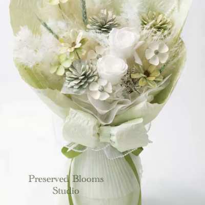 Pale green and white preserved bouquet with roses, small blossoms, and feathers wrapped in matching paper and bow