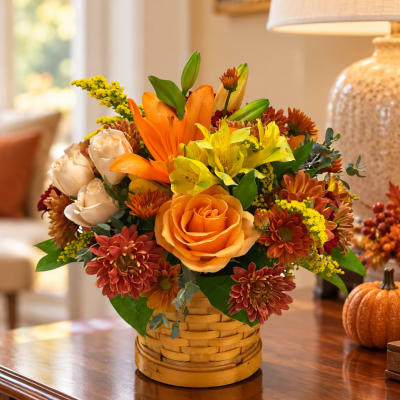 Autumn flower arrangement in a woven basket with orange and yellow blooms