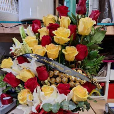 Bouquet of red and yellow roses in a white gift box with a red ribbon.