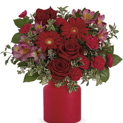Red roses and gerbera daisies in a red vase