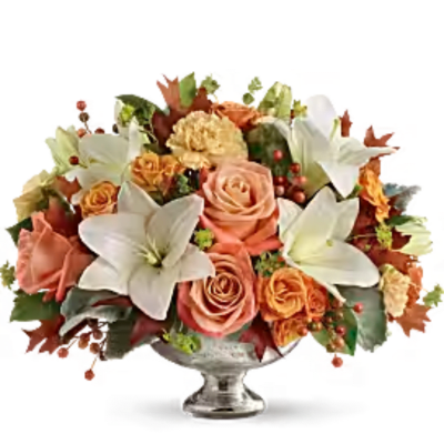 Peach roses and white lilies arranged in a clear glass vase
