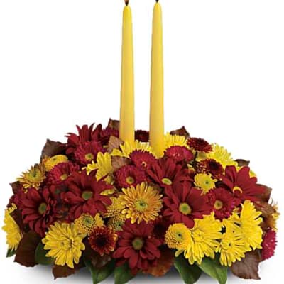 Red and yellow chrysanthemum arrangement with two tall yellow candles