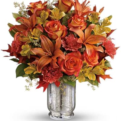 Orange and red floral arrangement in a silver vase