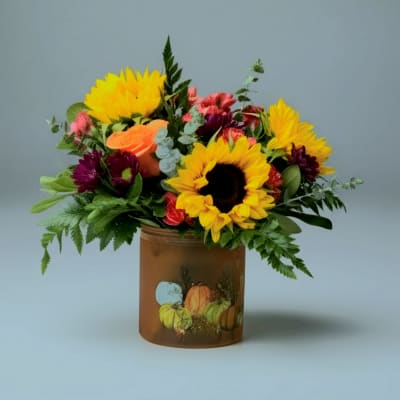 Sunflower and mixed flower arrangement in a brown glass vase