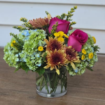 Pink roses and mixed blooms in a clear glass vase