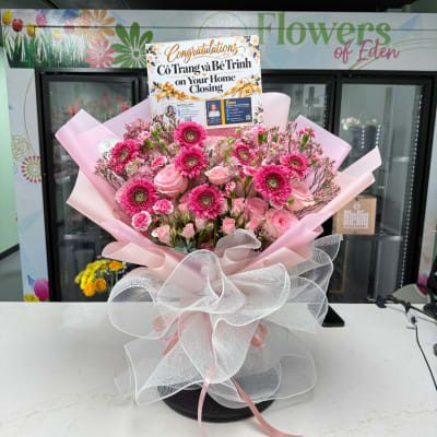 Pink flower bouquet with a congratulations sign in a shop setting