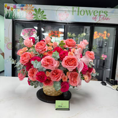 Basket arrangement of pink and coral roses with a sheer ribbon