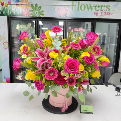 Pink and yellow mixed flower arrangement in a blush hatbox