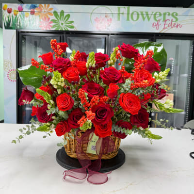 Basket arrangement of red roses with berries and ribbon