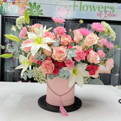 Pink and white floral arrangement in a round pink box