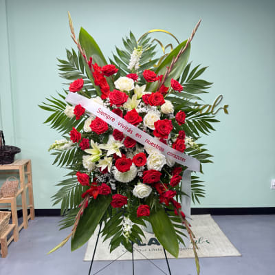 Standing floral spray of red and white roses with a condolence ribbon