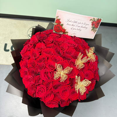 Large bouquet of red roses with a note card and gold butterfly picks
