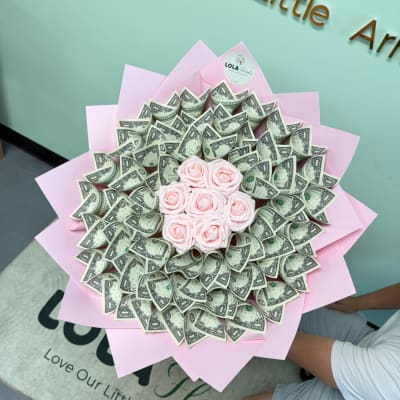 Bouquet of pink roses surrounded by folded dollar bills