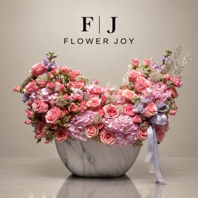 Pink rose and hydrangea arrangement in a marble-look vase
