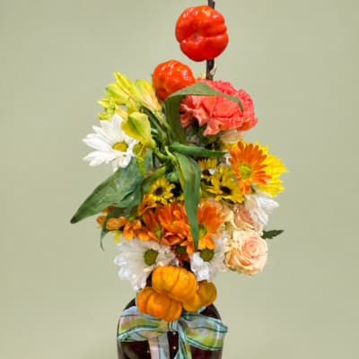 Colorful floral arrangement with pumpkins and a plaid bow in a vase