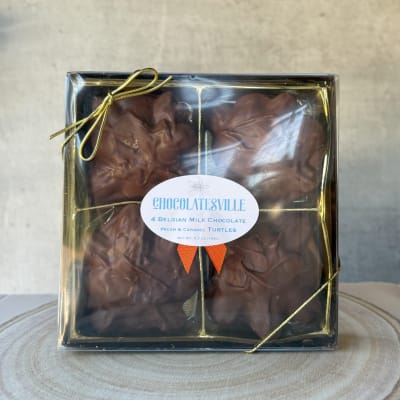 Box of chocolate turtles tied with a gold ribbon