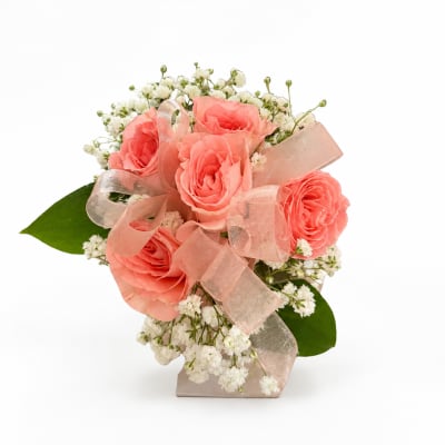 Pink roses with white baby's breath in a small vase, tied with a sheer ribbon