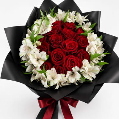 Red roses and white alstroemeria in black wrap with a red ribbon