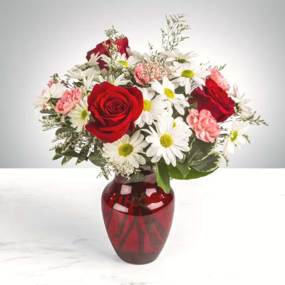 Red roses and white daisies in a red glass vase